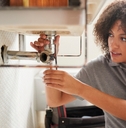 Female plumber fixing bathroom sink