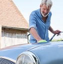 Mature Man Polishing Restored Classic Car Outdoors