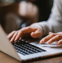  hands typing on a laptop