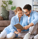 A couple look over plans together while sitting on the floor.