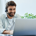 A man wears a headset while using his laptop.