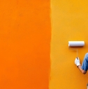 a person painting a vibrant orange wall