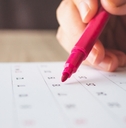 Hand with pen writing on calendar page closeup