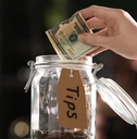 woman putting tips into glass jar