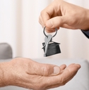real estate agent giving house key to senior man indoors