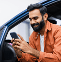 person looking at phone while leaning out of car
