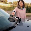 A woman frowns as she finds a parking ticket left on her windshield. 