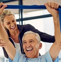 physical therapist helping a senior patient stretch with a stretch band