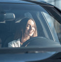 A woman smiles while driving her car.