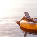 business woman working on a laptop in an inflatable ring in the water