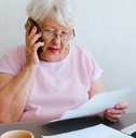 senior woman holding papers while talking on mobile phone