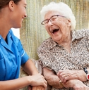 happy senior woman and nurse sitting in chair