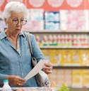 Shocked senior customer holding a long expensive grocery receipt