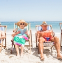 Senior friends reading books on beach chair 