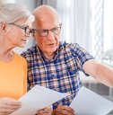 Worried senior couple checking bills using laptop
