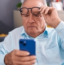 man looking at smartphone screen with vision problem