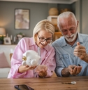 Senior couple count money from the piggy bank