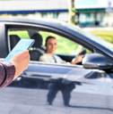 A man uses his phone to order a rideshare service. 