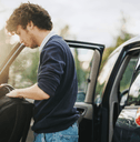 teen with backpack standing outside car