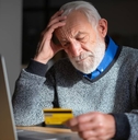 Senior man looking worried while holding a credit card