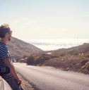 person leaning against car by side of road