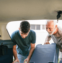 senior helping grandchild load car