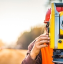 Person using large yellow surveyor camera zoomed with blurry background
