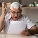 retired man in eyewear looking through paper document