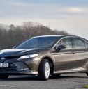 A man drives a dark gray Toyota Camry. 