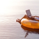 Woman working on a laptop in an inflatable ring in the pool