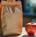 lunch bag with a handle sits on a countertop next to a red apple