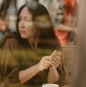 Gen X woman looking pensively out a window at a cafe