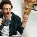 man with coffee mug working on laptop from home