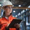 woman in a hard hat with a tablet working in a warehouse