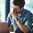 Stressed, tired and frustrated business man with headache at night from burnout or making mistake on laptop. 