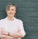 60-year-old woman in a cream blazer again a teal tile background