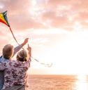 Senior couple flying kite by the water