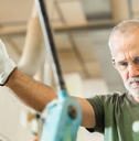 Older worker threading a steel bar in an industrial factory
