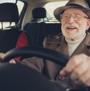 grey-haired man driving car