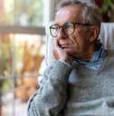 senior man looking out of window at home  