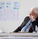 older man in suit at office contemplating