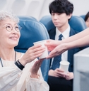 Asian older woman getting served drink in flight