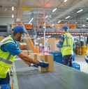 Warehouse employees loading boxes on conveyor belt in a processing center