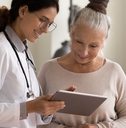 doctor and senior patient look at tablet screen