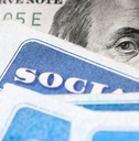 Dollar bill with Benjamin Franklin&#x27;s eyes looking and Social Security cards