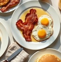 fried eggs and crispy bacon on white plates
