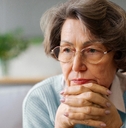 Older woman with hands crossed under her face looking worried