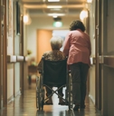 Female Caregiver and Elderly Woman in Hospital Hallway