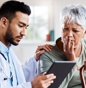 older woman sitting with doctor looking concerned