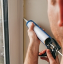 A man caulking a window